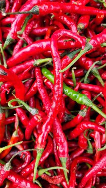 Green, Red and yellow hot chili peppers on display at a market stall. clipart