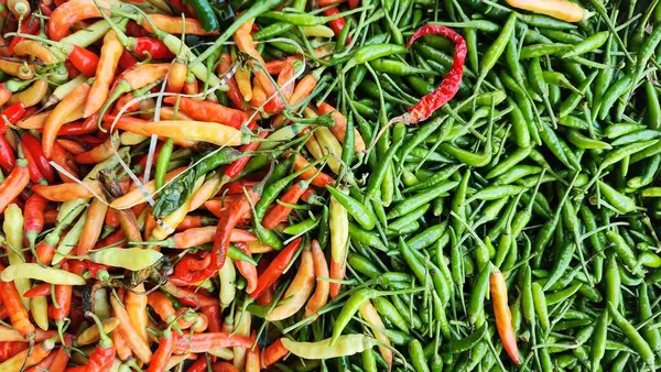 Yeşil, kırmızı ve sarı kırmızı kırmızı biberler bir markette sergileniyor.