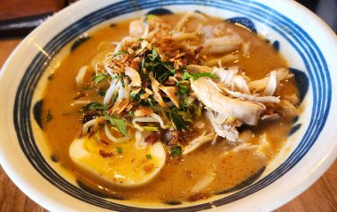 Mie Celor veya erişte celor çorbası, karides, tavuk ve balık ile ahşap masada.