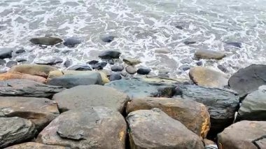 Dalgalar dalgaları dalgalanan kayalarla kumsalda