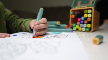 Sanat devam ediyor: Çocuk Boyama Kitabına Bağlandı. Boyama kitabında boya kalemleriyle boyama yapan bir çocuk. Yaratıcı Anlar: Pastel Boyalı Çocuk Boyama
