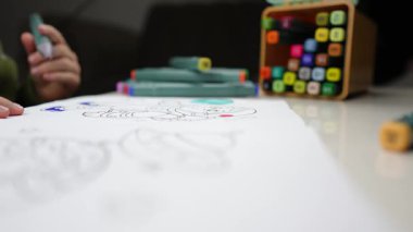 Sanat devam ediyor: Çocuk Boyama Kitabına Bağlandı. Boyama kitabında boya kalemleriyle boyama yapan bir çocuk. Yaratıcı Anlar: Pastel Boyalı Çocuk Boyama