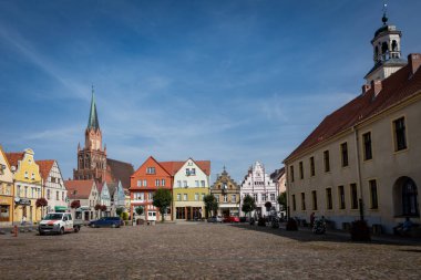 Trzebiatow, Polonya - 18 Eylül 2023: Ortaçağ Mariacki Kilisesi ve tarihi şehir merkezi pazar meydanındaki renkli konutlar. 