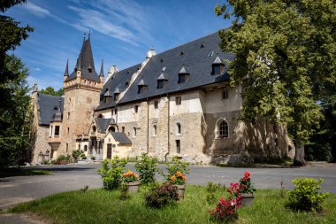 Sobotka Gorka, Poland - June 20, 2024: Front view of Sobotka Gorka castle in Sleza Massif, Lower Silesia voivodeship, beautiful park, flowers in foreground, no people. clipart