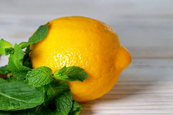 stock image Whole yellow lemon and fresh green mint on a light wooden background. Benefits and health. Close-up