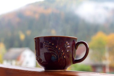 Kahvaltıda. Açık havada sıcak bir içecek ile büyük kahverengi bir bardak dağın arka planına yakın plan. Kahve, çay.