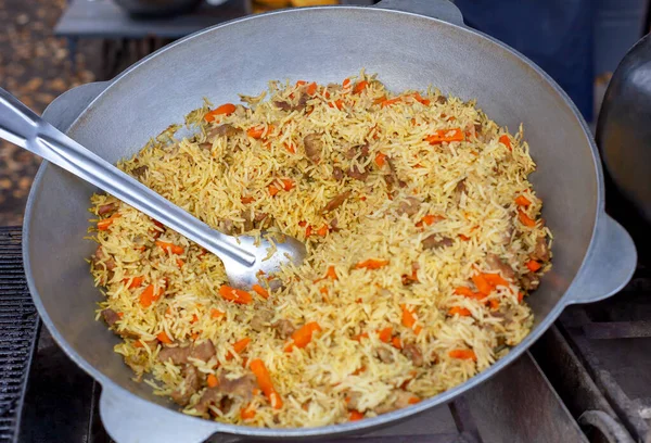 Stock image A large pot with freshly cooked pilaf. A large spoon for overlaying. Food court. Street food