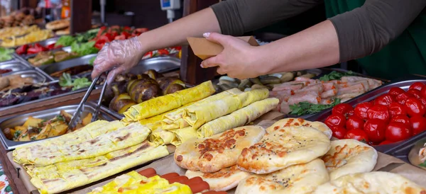 Yemek katı. Bir sürü farklı sokak yemeği. Manikürcü kadın elleri, tabağa patates koyuyor. Restoran yemekleri.