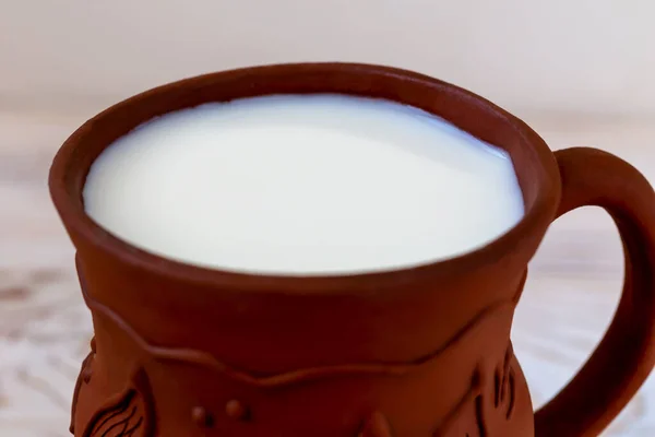 新鲜美味的牛奶在棕色黏土壶的特写 带有复制空间的轻型木制背景 — 图库照片
