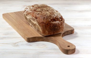 Tahtada taze pişmiş Litvanya ekmeği, beyaz ahşap bir arka plan.