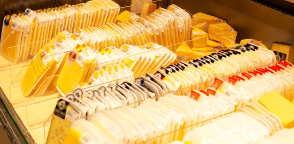 Showcase in a supermarket with rows of packaged cheeses. Trade, shops, business