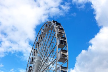 Açık mavi gökyüzü ve beyaz bulutların arka planında büyük dönme dolap. Romantik seyahatler. Yıldızlara daha yakın. Büyüme kavramı