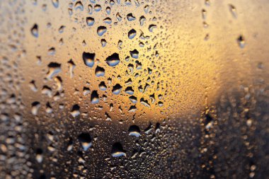 Camdaki damlaların arasından muhteşem bir gün batımı. Tasarımın ve ilhamın için mükemmel bir geçmiş. Seçmeli odak, ayrışma