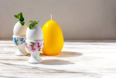 Paskalya. Yumurtalar tezgahta. Yapraklar filizlenir. Yakınlarda mum şeklinde sarı büyük bir yumurta var. Yeni hayat kavramı. Kopyalama alanı olan hafif arkaplan