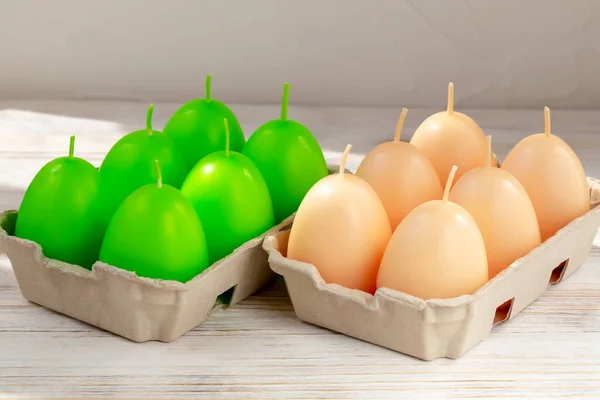Easter. Green and beige egg-shaped candles in trays. The concept of new life