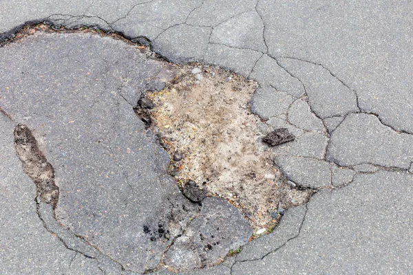 Broken asphalt on the sidewalk on the street. Pits, potholes on the road. City life