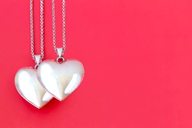 Two pendants on a chain in the form of a heart on a red background. Valentine's Day. The concept of love and loyalty