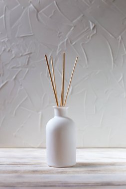 Perfume for the home. Aromatic reed diffuser in on a white background. The concept of peace, relaxation and enjoyment. White on white. Vertically