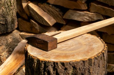 The ax is on a deck, next to a stack of chopped wood. Preparing for the winter. Harvesting firewood. Natural resources. Heating without gas