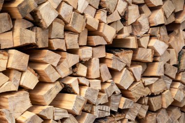 A wall of chopped firewood. Preparing for the winter. Harvesting firewood. Natural resources. Heating without gas. Background of dry chopped firewood. Wooden background. Natural texture.