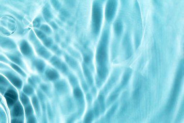 Ripples in light blue water. Textured background for your design. Selective focus, defocus