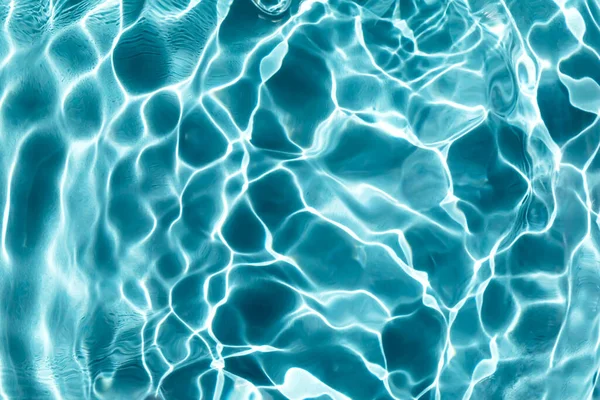 Waves and ripples on the water in sunlight. Pool, river, ocean. Blue textured background for your design. Selective focus, defocus