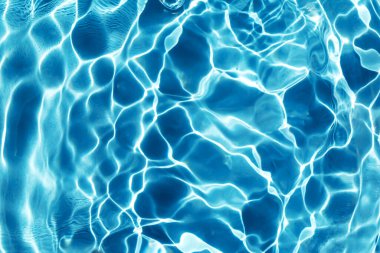 Waves and ripples on the blue water in sunlight. Pool, river, ocean. Blue textured background for your design. Selective focus, defocus