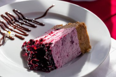 Çikolatayla süslenmiş beyaz tabakta taze üzümlü peynirli kek. Restoran servisi. Seçici odak