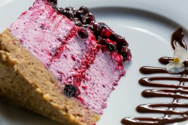 Çikolatayla süslenmiş beyaz tabakta taze, nefis pembe üzümlü peynirli kek. Restoran servisi. Seçici odak