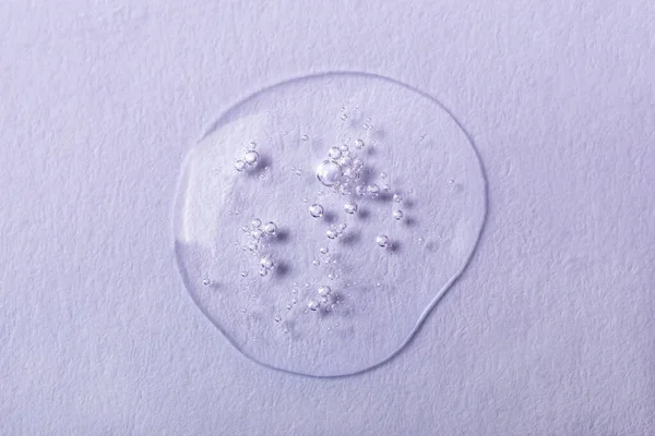 Drop of transparent liquid with bubbles on white background. Laboratory studies. Cosmetics, gel, transparent texture, lotion. Selective focus, defocus