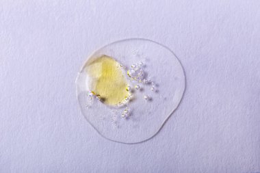 Beyaz arka planda sarı lekeli, köpüklü şeffaf sıvı damlası. Laboratuvar çalışmaları. Kozmetik, jöle, şeffaf doku, losyon. Seçmeli odak, ayrışma