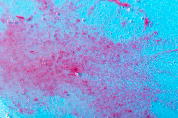Textured liquid background with red particles on blue background. Laboratory studies. Cosmetics, gel, transparent texture, lotion. Selective focus, defocus