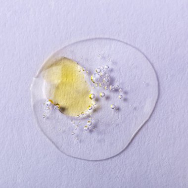 Beyaz arka planda sarı lekeli, köpüklü şeffaf bir sıvı damlası. Laboratuvar çalışmaları. Kozmetik, jöle, şeffaf doku, losyon. Seçmeli odak, ayrışma