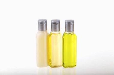 Beyaz arka planda üç küçük şişe kozmetik. Şampuan, duş jeli, vücut losyonu. Seyahat, seyahatler, oteller. Kozmetik modelleme, reklam.