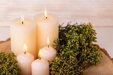 Yanan mumlar ve taze yeşil, tahta çemberde sarı koni ardıç dalları. Samimiyet, huzur, rahatlama kavramı.