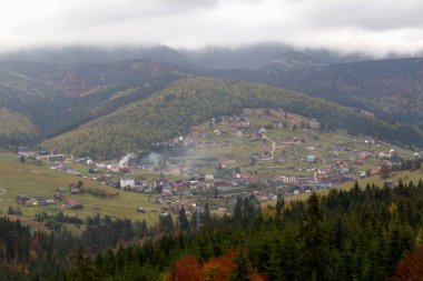 Sonbahar dağları, köyü bulutlu gökyüzünün altında. Karpatların güzelliği. Turizm ve seyahat