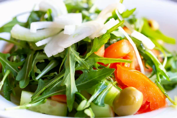 Friss Ízletes Egészséges Saláta Arugulával Paradicsommal Hagymával Uborkával Olívával Tányéron — Stock Fotó