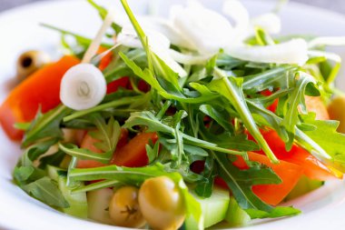 Taze vitaminli sebze salatası roka, zeytin, domates, salatalık ve tabakta beyaz soğan. Düzgün beslenme. Diyet ve sağlık. Seçmeli odak, ayrışma