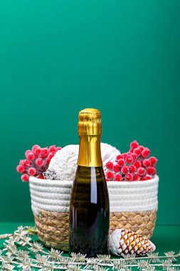 Hasır sepetin yanında bir şişe köpüklü şarap ve Noel süslemeleri. İyi tatiller. Modelleme. Dikey