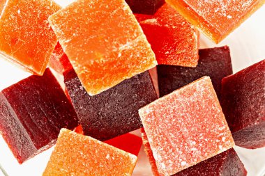 Kırmızı ve turuncu renkli marmelat küplerinin yakın plan görüntüsü, şekerle tozlanmış, şeker ya da bayram hediyesi için mükemmel. El yapımı şekerleme.