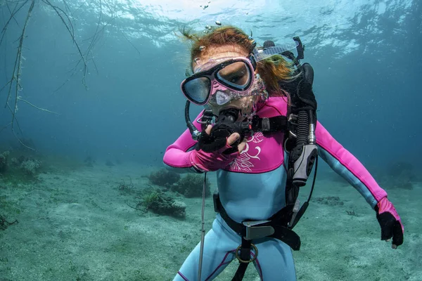 A little girl diver breathes into the regulator, blowing underwater bubbles in the pacific ocean, against the backdrop of clear sea water. Exploration of the underwater world, diving for children, sea