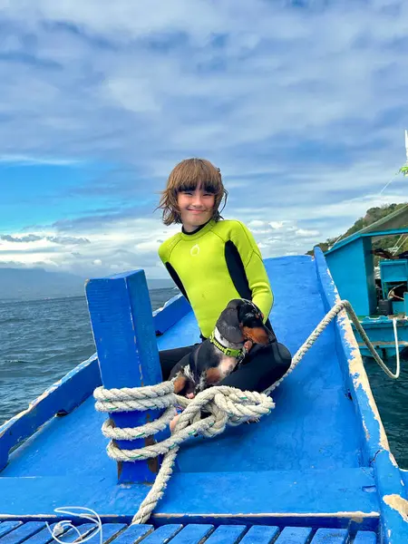 Mutlu genç bir kız gülümser, parlak mavi bir gökyüzünün zeminine karşı elinde bir köpekle bir teknede otururken kameraya bakar. Seyahat kavramı