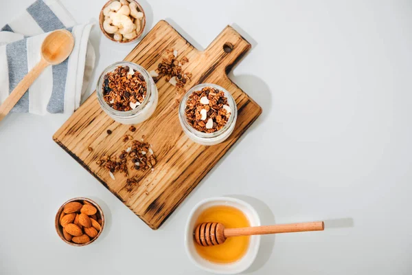 Böğürtlen, ahududu ve chia tohumlarıyla dolu cam kavanozlarda yoğurtlar ve ahşap bir tahtanın üzerinde beyaz bir arka planda mutfak havlusuyla tahıl gevreği. Sağlıklı beslenme kavramı. Düz yatıyordu