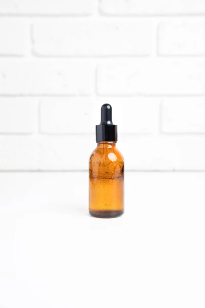 stock image One amber bottle with a pipette on a white table, selfcare cosmetic products. Front view