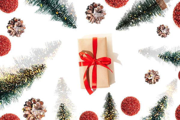 背景与礼物用红色带子 装饰螺丝 松果和红色闪光球与阴影白色背景捆绑 圣诞节的图案是平铺的 — 图库照片