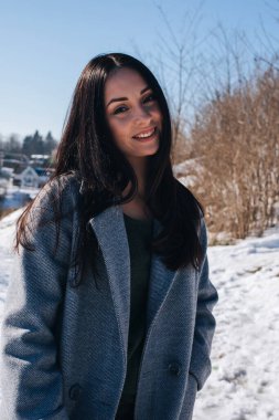Kışın karlı sokaklarda kahverengi gözlü, güzel siyah saçlı bir kızın portresi. Ön görünüm