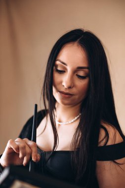 Siyah elbiseli, fırçalı bir kadın ressam. Bir kızın portresi, ön manzara.