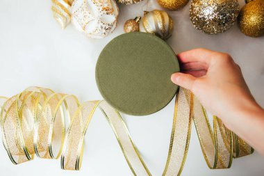 Yeni yıl ve Noel geçmişi. Sarı arka planda, melek saçı ve altın dekoratif kurdeleli yeşil bir hediye. Üst görünüm