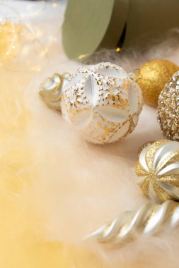 Yeni yıl ve Noel geçmişi. Altın dekoratif kurdele ve yeşil yuvarlak hediye. Sarı arka planda, melek saçlı. Üst görünüm