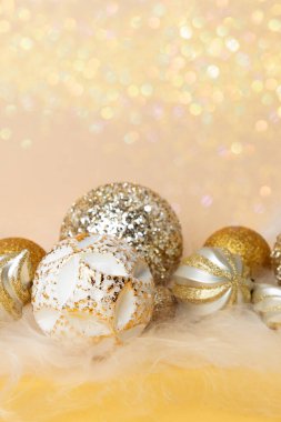 Yeni yıl ve Noel geçmişi. Sarı arka planda altın ve beyaz renkli, melek saçlı Noel topları. Ön görünüm